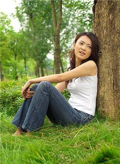 靠着树干坐在草地上的年轻女人