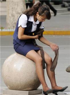 街拍: 穿着制服的美女, 坐在石球上研究刚买的丝袜