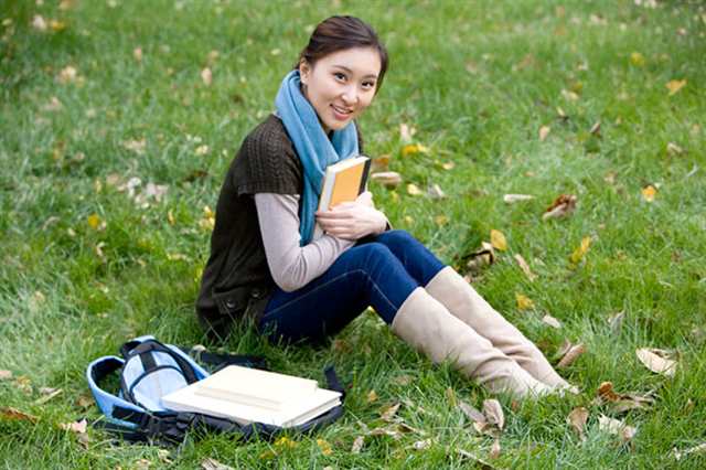 青年女子坐在草地上看书(点击浏览下一张趣图)