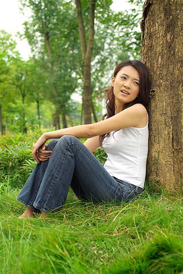 靠着树干坐在草地上的年轻女人(点击浏览下一张趣图)