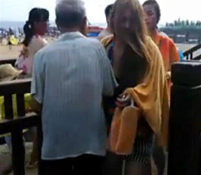 老人站在海滨浴场出口处专撞女子胸部