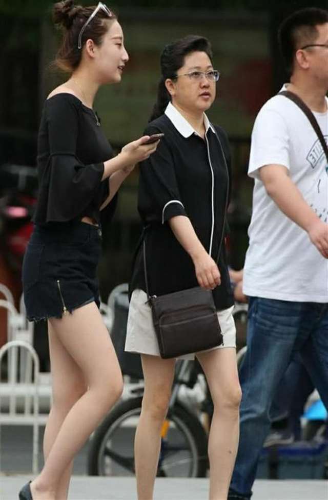 丰腴少妇黑色抹胸显一字香肩,牛仔热裤勾勒出丰满翘臀